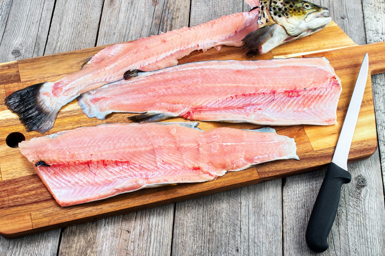 a boning knife next to fish meat