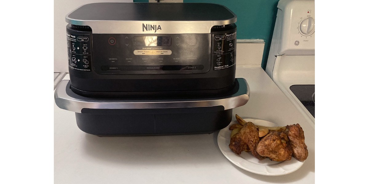 Ninja Foodi FlexBasket Air Fryer next to plate of baked chicken wings and fries Ninja Foodi FlexBasket Air Fryer next to plate of baked chicken wings and fries