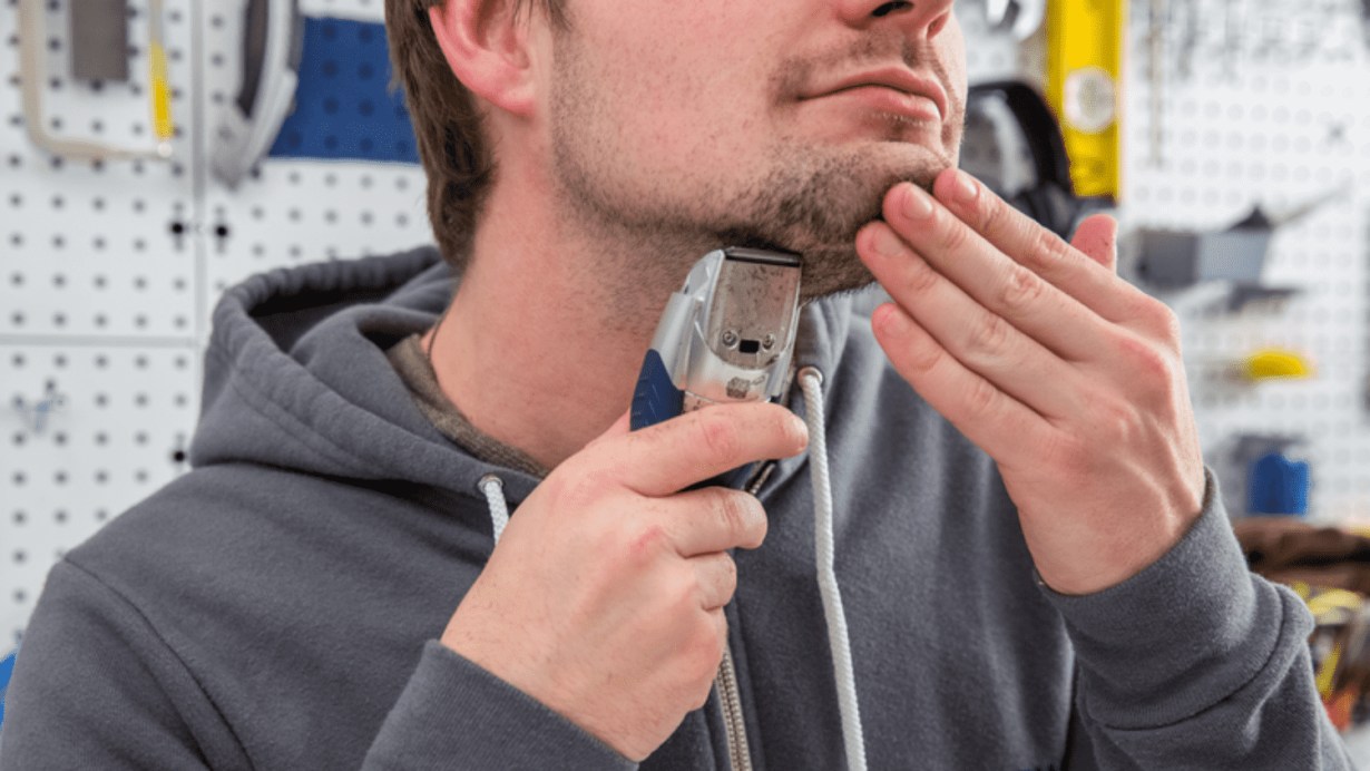 A young man using beard trimmer  A young man using beard trimmer
