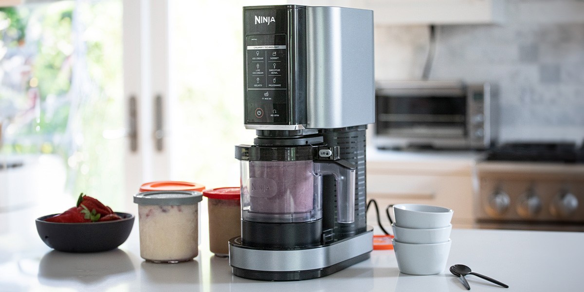 Ninja Creami Deluxe with pink ice cream inside on kitchen counter
