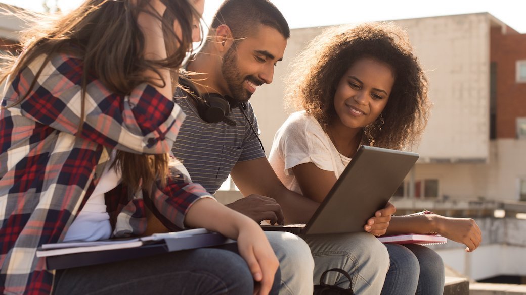 Three people on a couch looking at a laptop