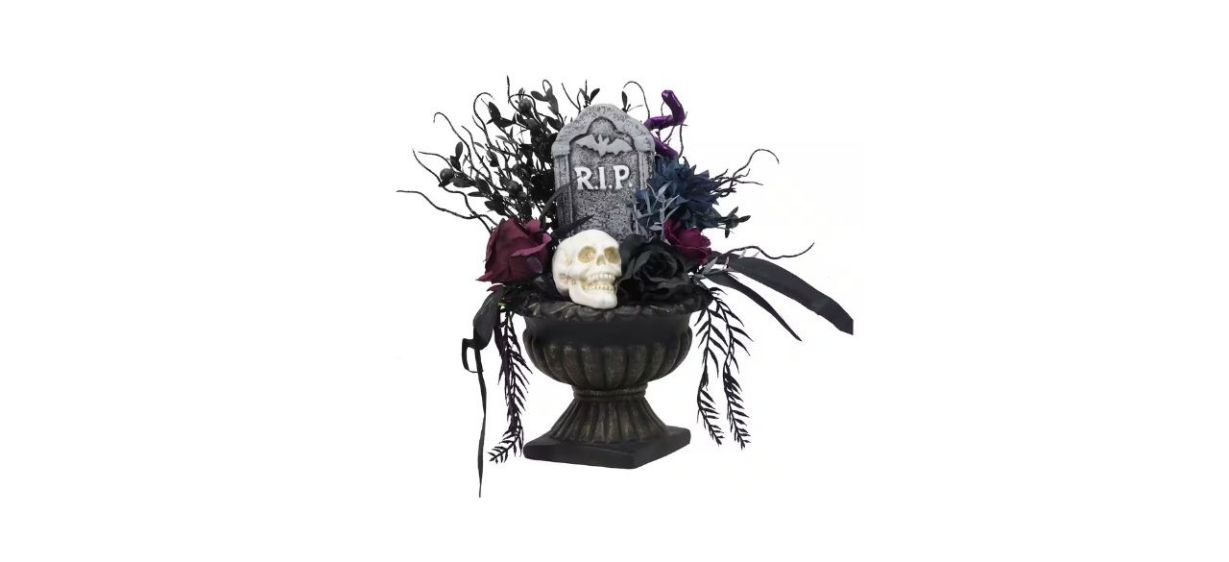 black and maroon flowers and black plant parts with skull and tombstone decorations in a black planter