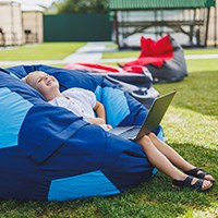 a child using a laptop while sitting on a large bean bag